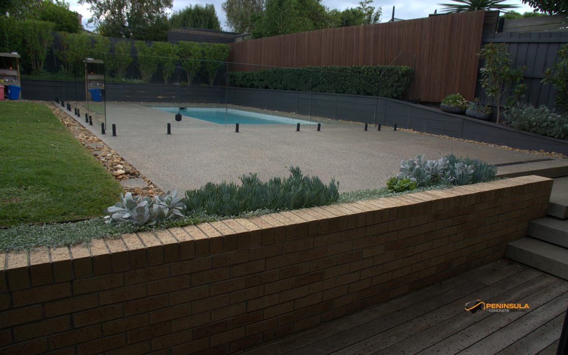Pool area with sealed paving, glass fence and landscaped brick planter